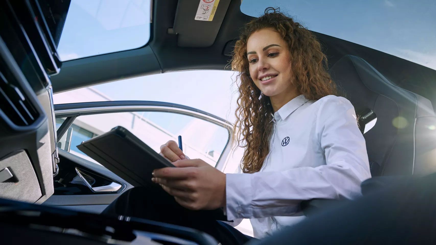 Eine Volkswagen Servicetechnikern sitzt mit ihrem Tablet in einem ID.